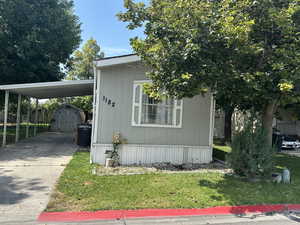 View of side of home with a storage unit, concrete driveway, and an attached carport