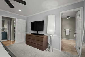 Bedroom with light colored carpet, crown molding, ensuite bath, recessed lighting, and a ceiling fan
