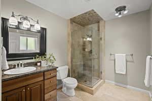 Full bath with vanity, a shower stall, and light tile patterned flooring