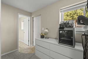 Corridor featuring light carpet and baseboards