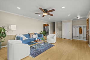 Living area with crown molding, light wood-style flooring, recessed lighting, stairs, and ceiling fan