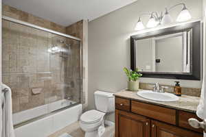 Full bath with enclosed tub / shower combo, vanity, and light tile patterned flooring