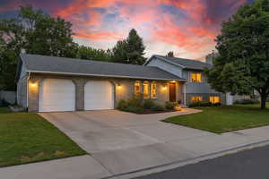 Tri-level home featuring driveway, an attached garage, brick siding, and a shingled roof