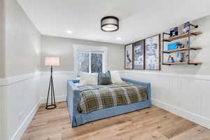 Bedroom with wood finished floors, wainscoting, and recessed lighting