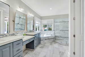 Full bathroom with a stall shower, crown molding, a bath, double vanity, and light marble finish flooring