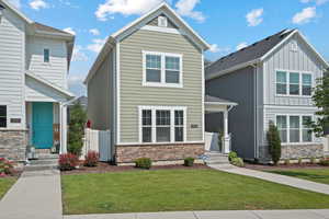 View of front of home featuring stone siding, a front yard, and board and batten siding