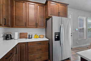 Kitchen with stainless steel fridge, a textured ceiling, and dark wood finished floors