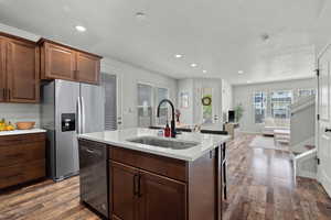 Kitchen featuring appliances with stainless steel finishes, dark wood-style flooring, recessed lighting, dark brown cabinets, and a kitchen island with sink