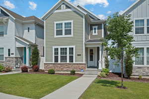 View of front facade with stone siding and a front lawn