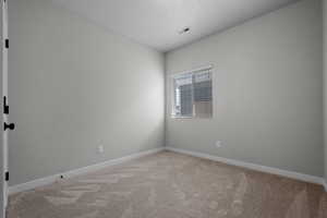 Spare room featuring light carpet and baseboards
