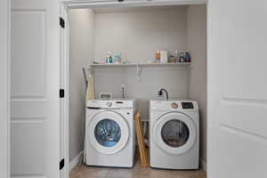 Laundry area featuring light tile patterned flooring and independent washer and dryer