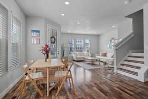Dining room featuring dark wood-style flooring, recessed lighting, and stairs