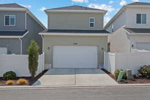 View of front of house with stucco siding, a shingled roof, driveway, and a garage