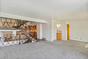 Unfurnished living room with carpet flooring and stairs