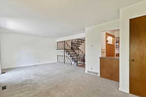 Unfurnished room featuring carpet flooring and stairs