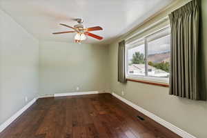 Unfurnished room with dark wood-type flooring and ceiling fan
