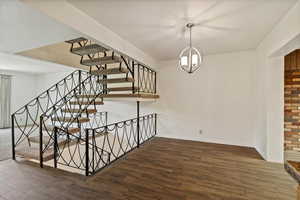 Stairs featuring wood finished floors and a chandelier