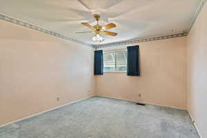 Carpeted empty room with a ceiling fan and baseboards