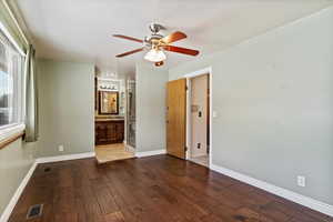 Unfurnished bedroom featuring dark wood-style floors, ceiling fan, and connected bathroom