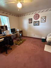 Carpeted office space featuring a textured ceiling and ceiling fan