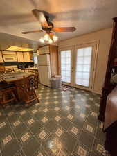 Kitchen featuring a textured ceiling, french doors, a ceiling fan, white appliances, and dark floors