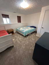 Bedroom with dark colored carpet and a textured ceiling