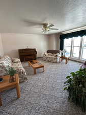 Living room with carpet, a textured ceiling, and ceiling fan