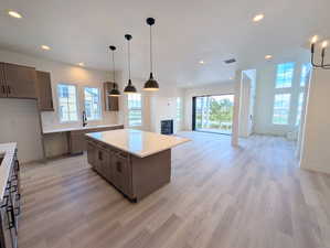 Kitchen featuring decorative light fixtures, recessed lighting, dark brown cabinetry, open floor plan, and a kitchen island