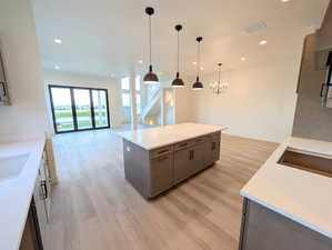Kitchen with a center island, open floor plan, light wood finished floors, recessed lighting, and decorative light fixtures