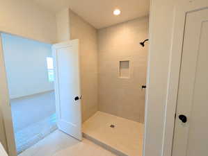 Primary Bathroom with a tile shower, carpet, tile patterned flooring, and recessed lighting