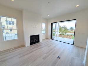 Unfurnished living room featuring recessed lighting, a fireplace, and light wood finished floors
