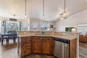 Kitchen with decorative light fixtures, a center island with sink, stainless steel dishwasher, healthy amount of natural light, and lofted ceiling