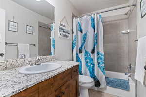 Bathroom featuring shower / tub combo with curtain, vanity, light tile patterned floors, and a textured ceiling
