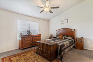 Bedroom with vaulted ceiling, light colored carpet, and a ceiling fan