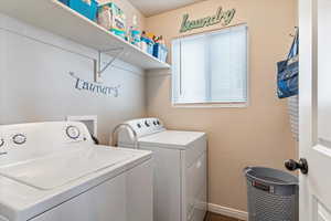 Washroom with washing machine and clothes dryer and baseboards