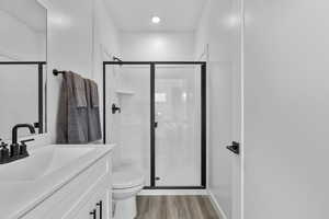 Full bath with vanity, a shower stall, and light wood-style flooring
