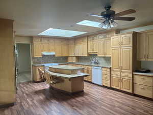 Kitchen featuring ornamental molding, a skylight, a breakfast bar, dark wood finished floors, and a center island