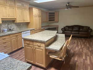 Kitchen featuring backsplash, a breakfast bar area, a center island, ornamental molding, and dark wood-style floors