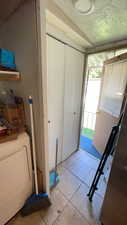 Washroom featuring light tile patterned flooring, a textured ceiling, and washer / clothes dryer