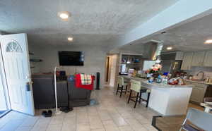 Living area featuring a textured ceiling, light tile patterned flooring, and recessed lighting