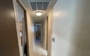 Corridor featuring light tile patterned floors, cooling unit, and attic access