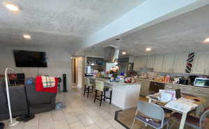 Kitchen with a kitchen breakfast bar, a textured ceiling, pendant lighting, recessed lighting, and light tile patterned flooring
