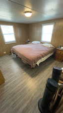 Bedroom with wood finished floors, wooden walls, and a textured ceiling