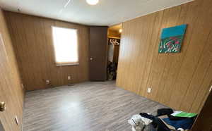 Unfurnished bedroom with wooden walls and wood finished floors