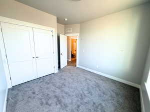 Unfurnished bedroom featuring carpet and a closet