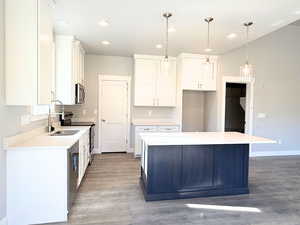 Kitchen with white cabinetry, decorative light fixtures, stainless steel appliances, light wood-type flooring, and recessed lighting