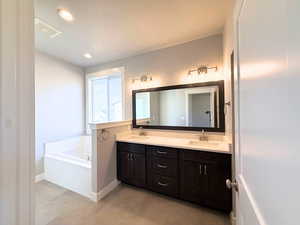 Bathroom featuring double vanity, a garden tub, and recessed lighting