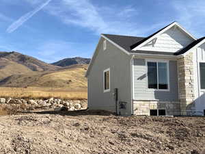 View of side of property with stone siding, a shingled roof, and a mountain view