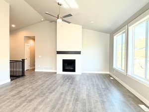 Unfurnished living room with light wood-style flooring, vaulted ceiling, a fireplace, recessed lighting, and ceiling fan
