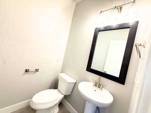 Half bathroom featuring baseboards and toilet